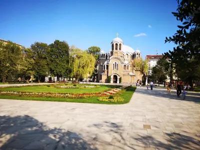 a building with a clock tower in a park at Graf Ignatiev - 3BR APART in Sofia