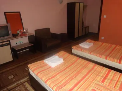 a hotel room with two beds and a chair at Kestenite Family Hotel in Samokov