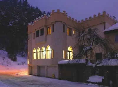 a large house in the snow at night at The Castle Hotel in Samokov