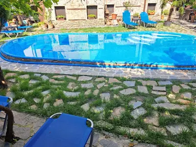 a swimming pool with blue chairs and chairs in a yard at Keremidchieva Kushta Guest House in Sandanski
