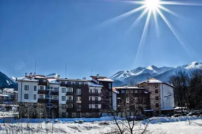 a building in the snow with mountains in the background at Mountain View Resort Studio in Bansko