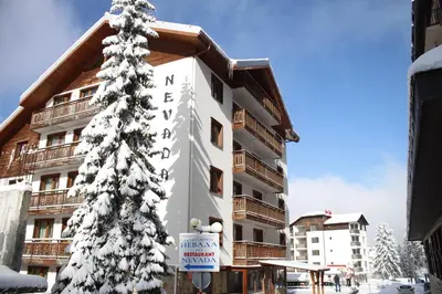 a snow covered christmas tree in front of a building at Nevada Aparthotel in Pamporovo