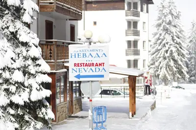a sign in front of a house in the snow at Nevada Aparthotel in Pamporovo