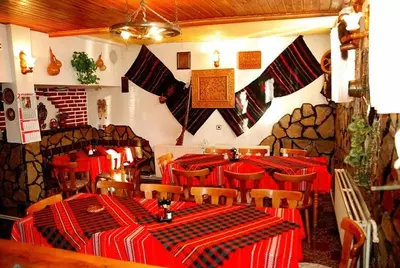 a restaurant with tables and chairs with red and black tables at Mavrikova Kushta in Bansko