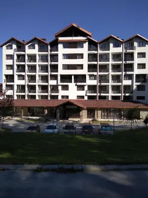 a large white building with cars parked in a parking lot at Apartment in Borovets Gardens C17 in Borovets