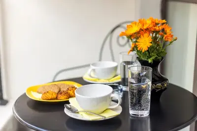 a black table with plates of food and a vase with flowers at Vacation Apartment in Plovdiv