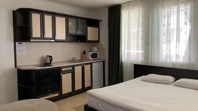 a bedroom with a bed and a kitchen with cabinets at Grand Monastery Private Apartments in Pamporovo