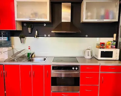 a kitchen with red cabinets and a stove and a microwave at Lovely place in Sofia