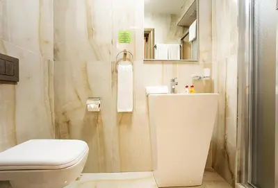 a white bathroom with a toilet and a shower at Sofia Place Hotel by HMG in Sofia