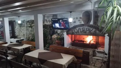 a fireplace in a restaurant with two tables and a tv at Hotel Bolyarka in Melnik