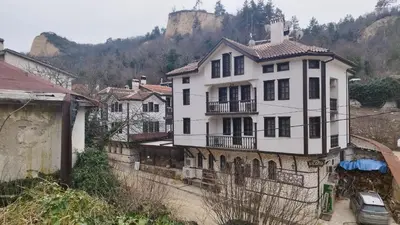 a white house on top of a stone wall at Hotel Bolyarka in Melnik