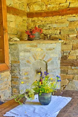 a stone fireplace with a vase of flowers on a table at Kalinia Guesthouse B&B in Kovachevitsa