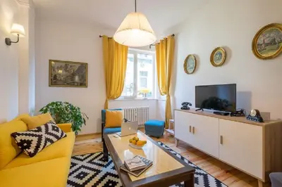 a living room with a yellow couch and a tv at Downtown Wanderlust Apartment in Sofia