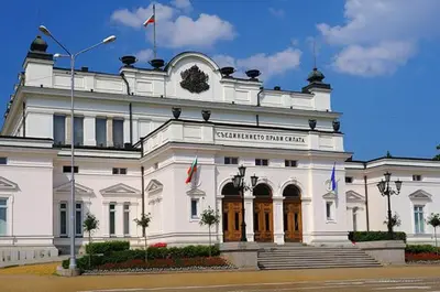 a white building with flags on top of it at Top Place in Downtown in Sofia