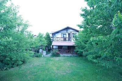 a house in the middle of a yard with trees at Belcheva kashta in Banya