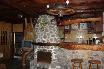 a living room with a stone fireplace and a television at Belcheva kashta in Banya