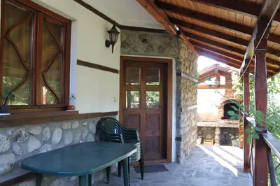 a porch with a table and a wooden door at Belcheva kashta in Banya