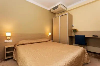 a bedroom with a bed and a desk and a chair at Geneva Hotel in Sofia