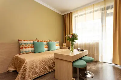 a bedroom with a bed with a table and a vase of flowers at Geneva Hotel in Sofia