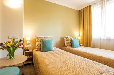a hotel room with two beds and a vase of flowers at Geneva Hotel in Sofia