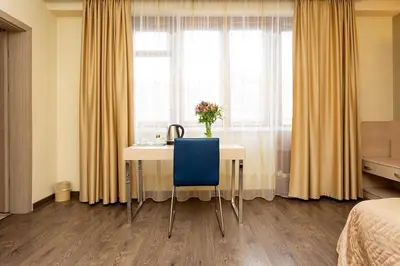 a bedroom with a desk with a blue chair and a window at Geneva Hotel in Sofia