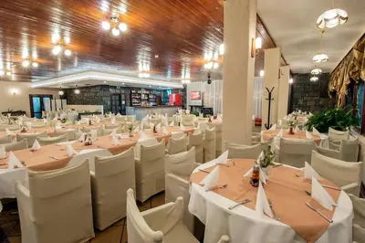a banquet hall with tables and white chairs at Hotel Prespa in Pamporovo