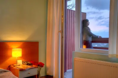 a woman looking out the window of a bedroom at Hotel Prespa in Pamporovo