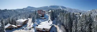 a ski resort with snow covered buildings and a mountain at Hotel Prespa in Pamporovo