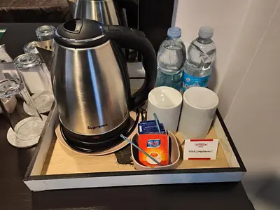 a tea kettle and cups on a tray with water bottles at Hotel Ihtiman in Ikhtiman