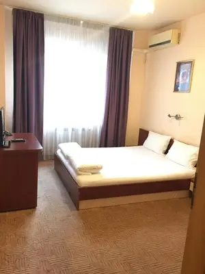 a bedroom with a bed and a large window at Hotel Galant in Sofia