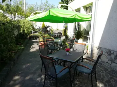 a group of tables and chairs with a green umbrella at Hotel Galant in Sofia