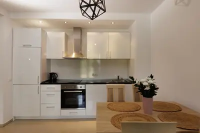 a kitchen with white cabinets and a table with a vase of flowers at Saint George Palace Aparthotel in Bansko