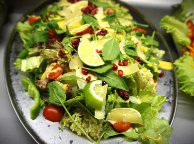 a plate of salad with lettuce and tomatoes and lime slices at Pirin River Ski, Fun and Family in Bansko