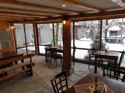 a dining room with tables and chairs and windows at Mamin Kolio in Bansko