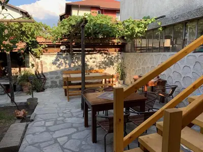 a patio with tables and benches and a balcony at Mamin Kolio in Bansko