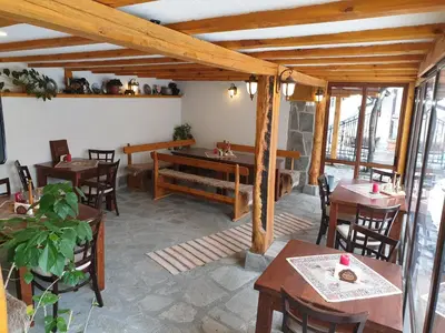 a restaurant with wooden tables and chairs in a room at Mamin Kolio in Bansko