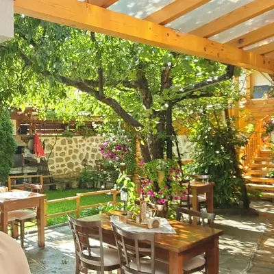a patio with tables and chairs under a tree at Mamin Kolio in Bansko
