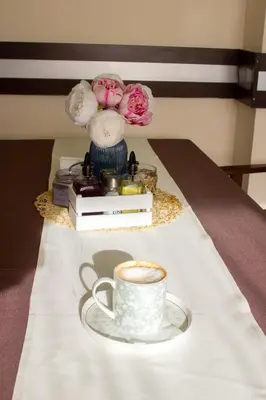 a cup of coffee and a vase with flowers on a table at Meteor Family Hotel in Chepelare