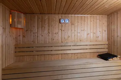 a wooden sauna with a bench and two clocks at Elitza Villa in Pamporovo