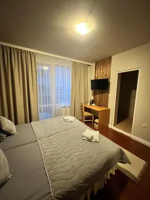 a hotel room with a large bed and a desk at Zasheva Kushta Guesthouse in Bansko