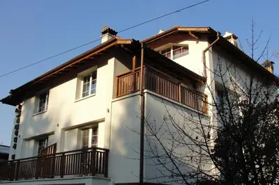 a white house with a balcony on top of it at Zasheva Kushta Guesthouse in Bansko
