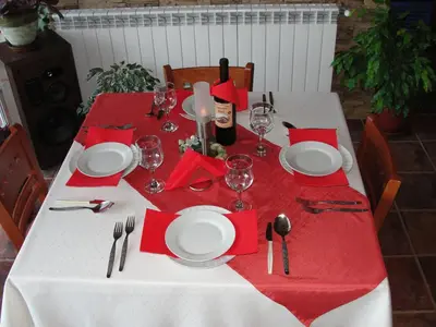 a table with red napkins and plates and wine glasses at Zasheva Kushta Guesthouse in Bansko