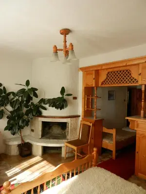 a living room with a fireplace and a chair at Damianka Guest House in Bansko