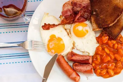 a plate of breakfast food with eggs bacon beans and toast at Bariakov Family Hotel in Bansko