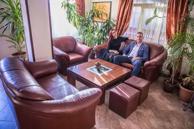 a man and woman sitting on a couch in a living room at Bariakov Family Hotel in Bansko