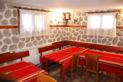 a dining room with a red table and chairs at Vien Guest House in Bansko