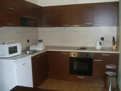 a kitchen with wooden cabinets and a microwave and a stove at Fortuna Apartments in Bansko