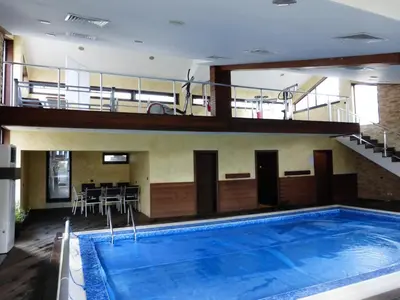 a large swimming pool in a building with a balcony at Fortuna Apartments in Bansko