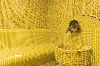 a yellow tiled bathroom with a toilet and a tub at Elina Hotel in Pamporovo