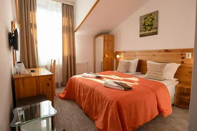 a hotel room with a bed with an orange blanket at Vezyuva House in Bansko